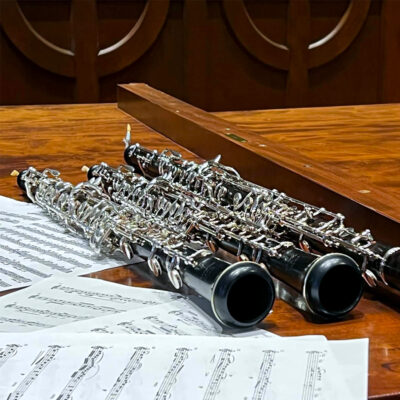 Image of three oboes next to sheet music on top of an organ.